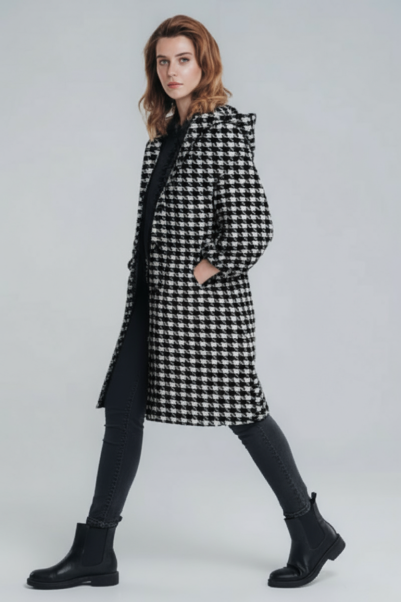 A person with shoulder-length hair wears the looselyboho HOUNDSTOOTH WINDBREAKER, black pants, and ankle boots against a light gray background.