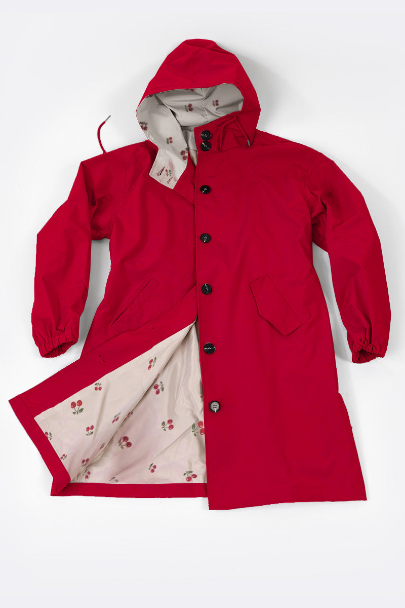 A red "Water Resistant Oversized Hooded Windbreaker Rain Jacket" from The WJacket is displayed on a white background. The coat exudes timeless style with long sleeves and elasticized cuffs, a front button closure, and two large pockets. Its versatility is highlighted by an interior lining adorned with rare beautiful colors in a small red and green floral pattern.
