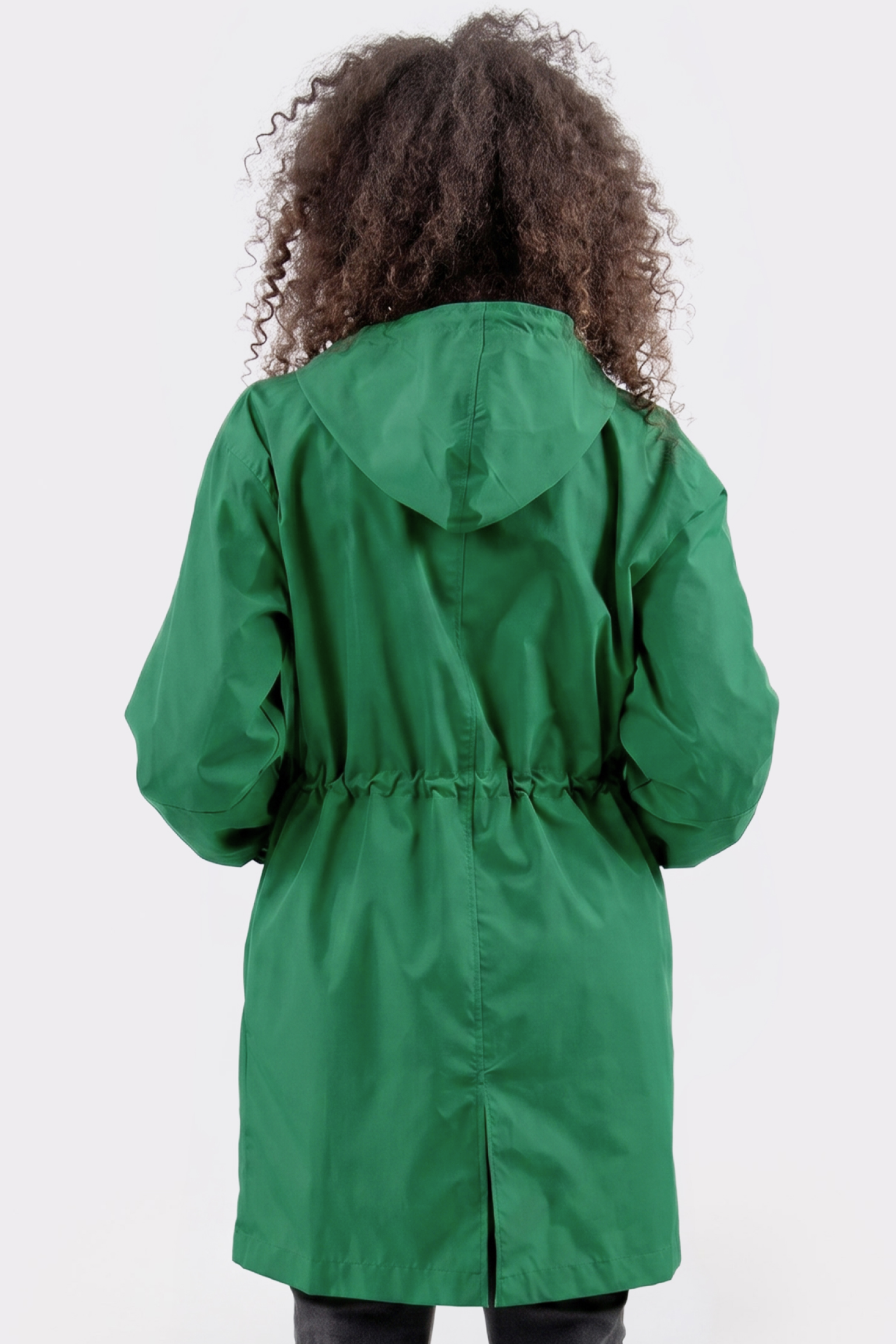 A person with curly hair faces away from the camera, wearing The Water Resistant Hooded Oversized Windbreaker Rain Jacket in green, featuring a cinched waist, set against a plain light background.