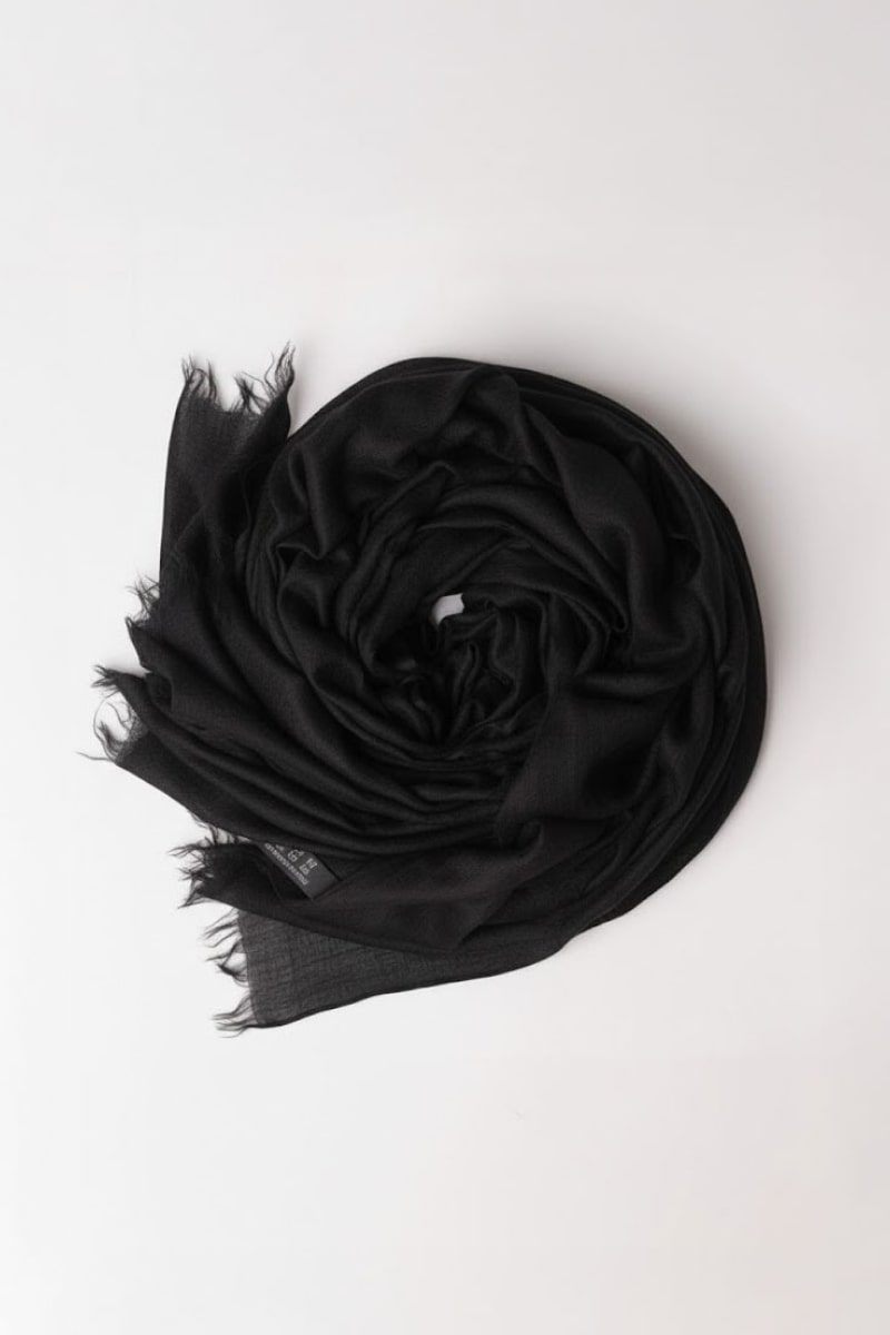 The looselyboho Noir Eclipse 100% Cashmere Scarf, featuring frayed edges, is styled in a circular shape on a simple white background.