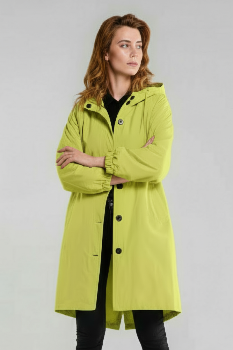 A woman stands with arms crossed, wearing the SUNLIT YELLOW WINDBREAKER by looselyboho over black pants and a black top, set against a plain light gray background.